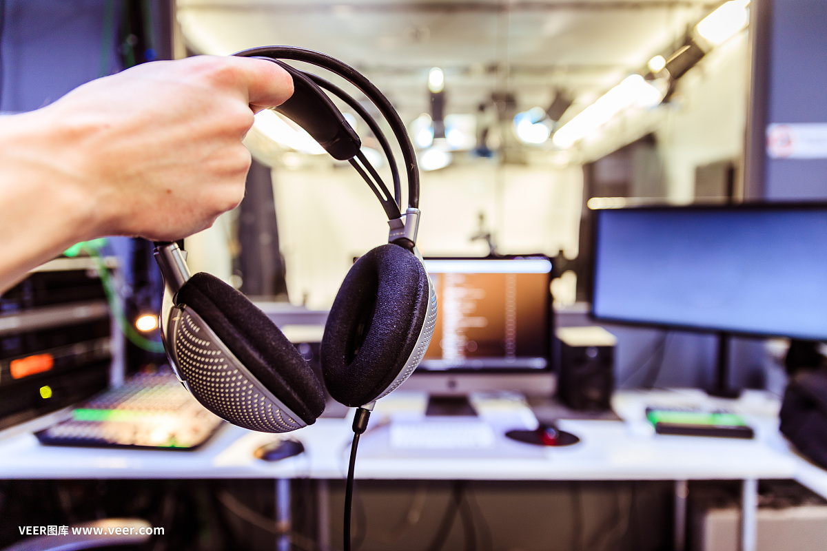 錄音室錄音:一個(gè)戴著耳機(jī)的年輕人正坐在錄音室里,錄音室的背景模糊不清